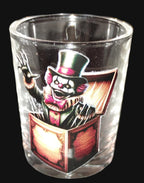 Glass shot glass with a clown design on a dark surface