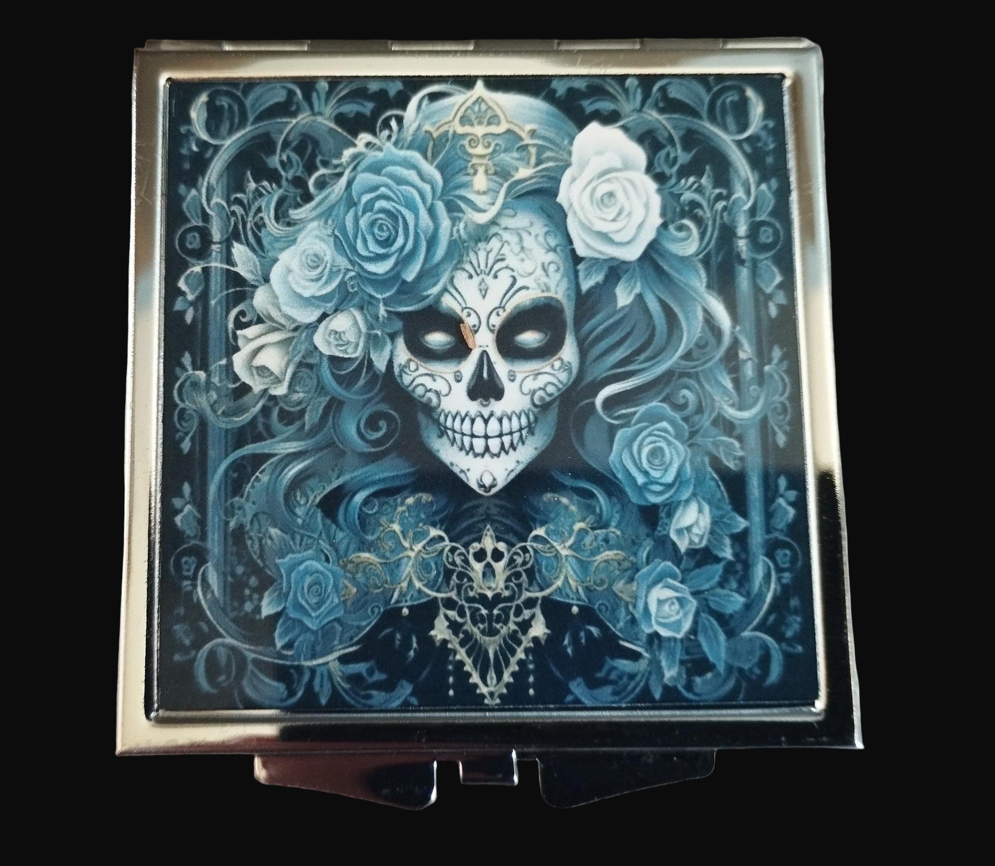Compact mirror with a skull and floral design on a wooden surface