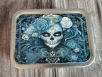 Decorative tin with a  skull and floral design on a wooden surface