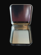 Metallic square tin with a lid on a black surface 