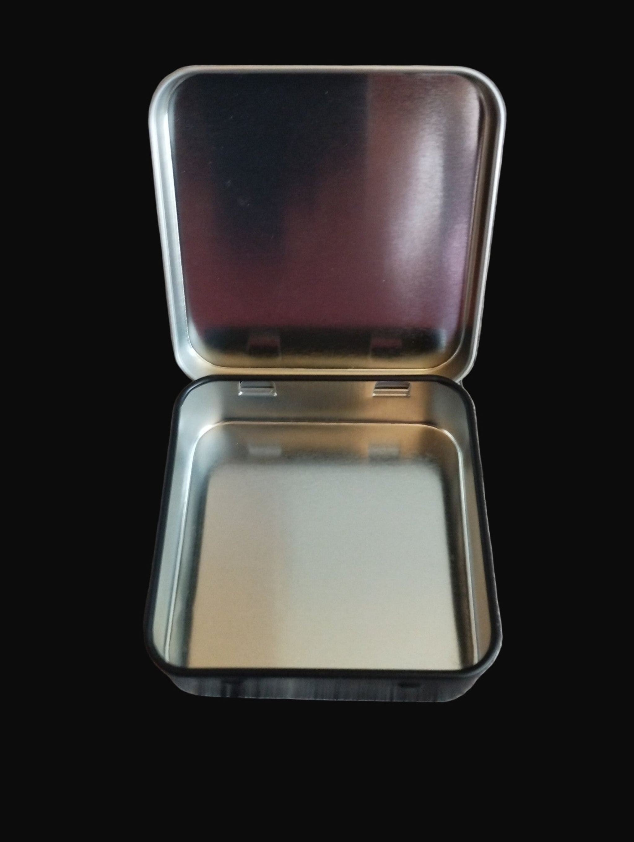 Metallic square tin with a lid on a black surface 