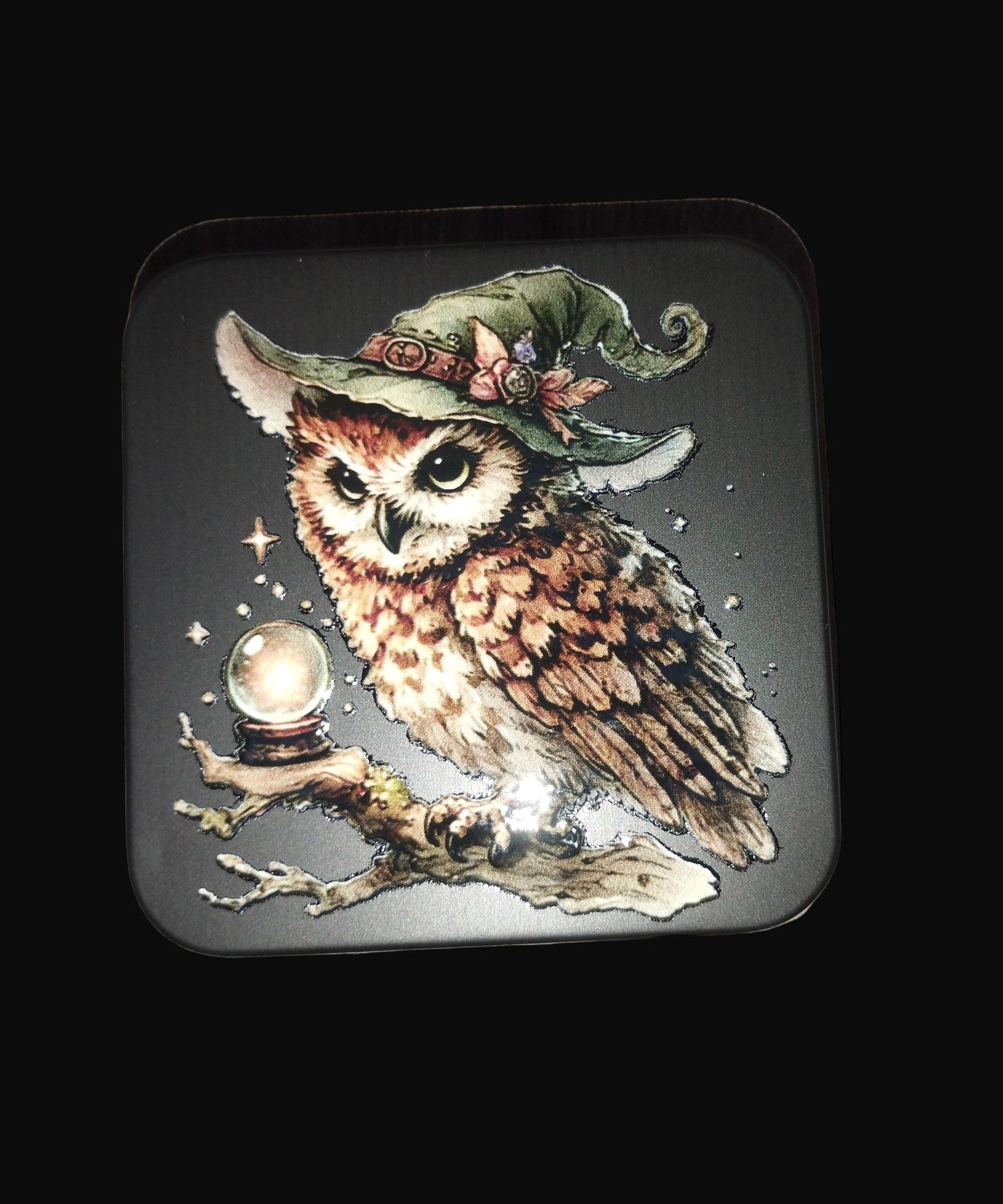 Decorative coaster with an owl wearing a witch hat and holding a crystal ball .