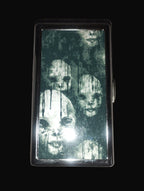 Cigarette case with ghostly faces design on a wooden surface