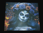 Decorative mat with a design of a person with skull makeup and floral headpiece on a wooden surface.