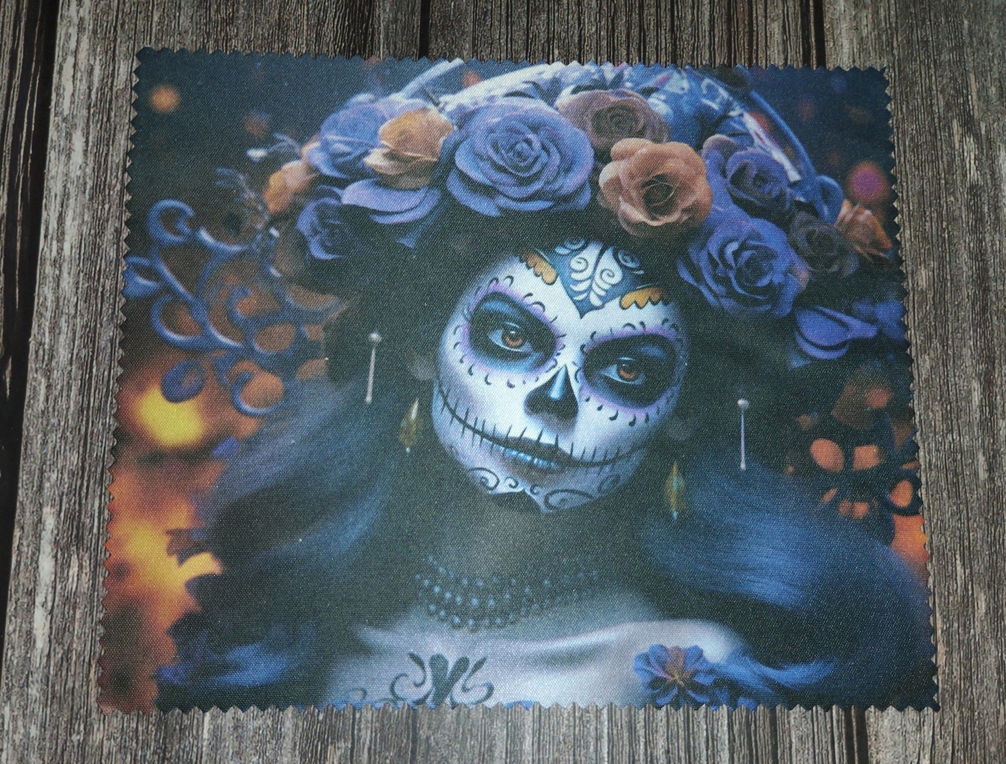 Decorative mat with a design of a person with skull makeup and floral headpiece on a wooden surface.