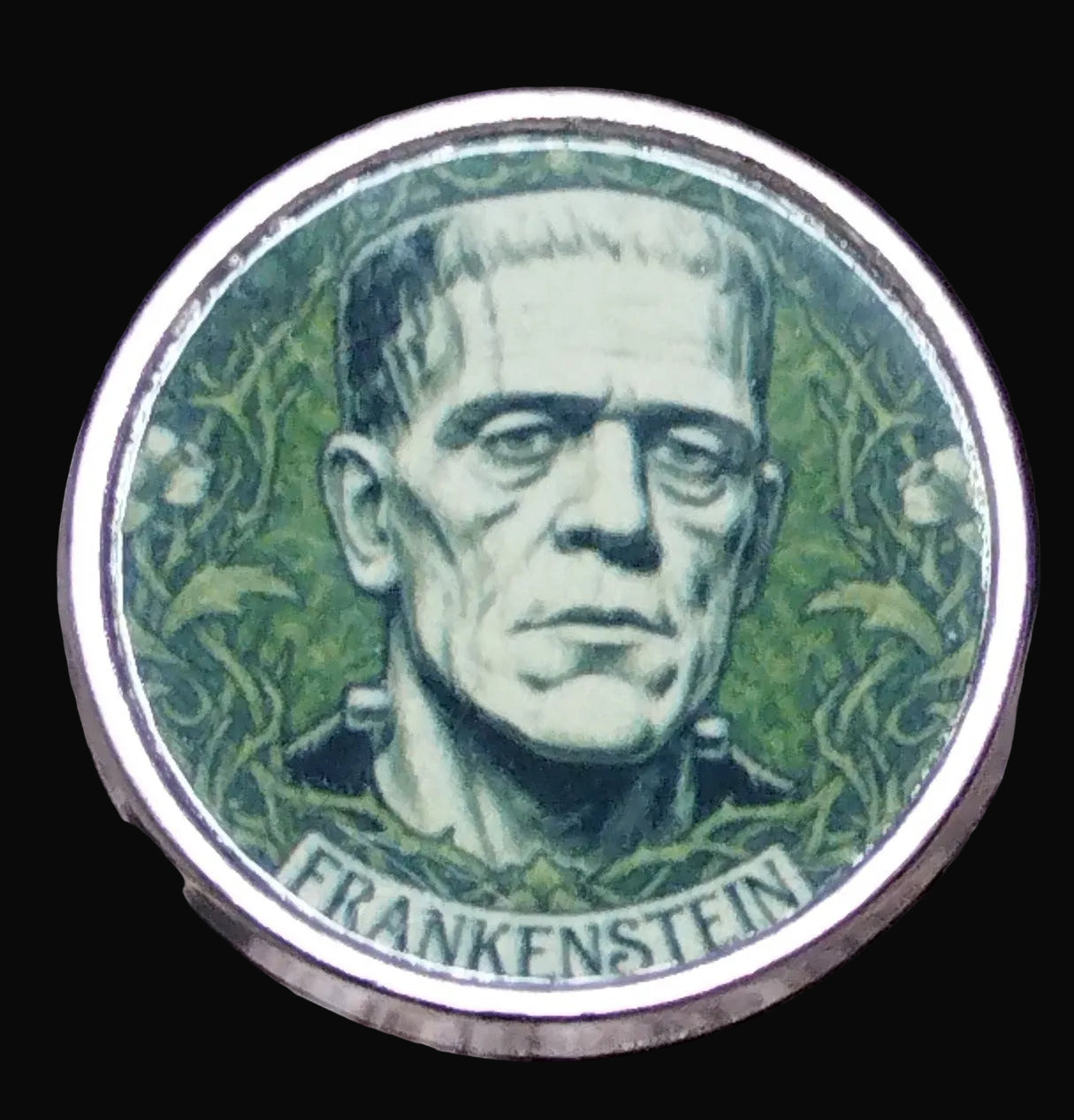 Circular badge with a green illustration of Frankenstein's monster on a wooden surface