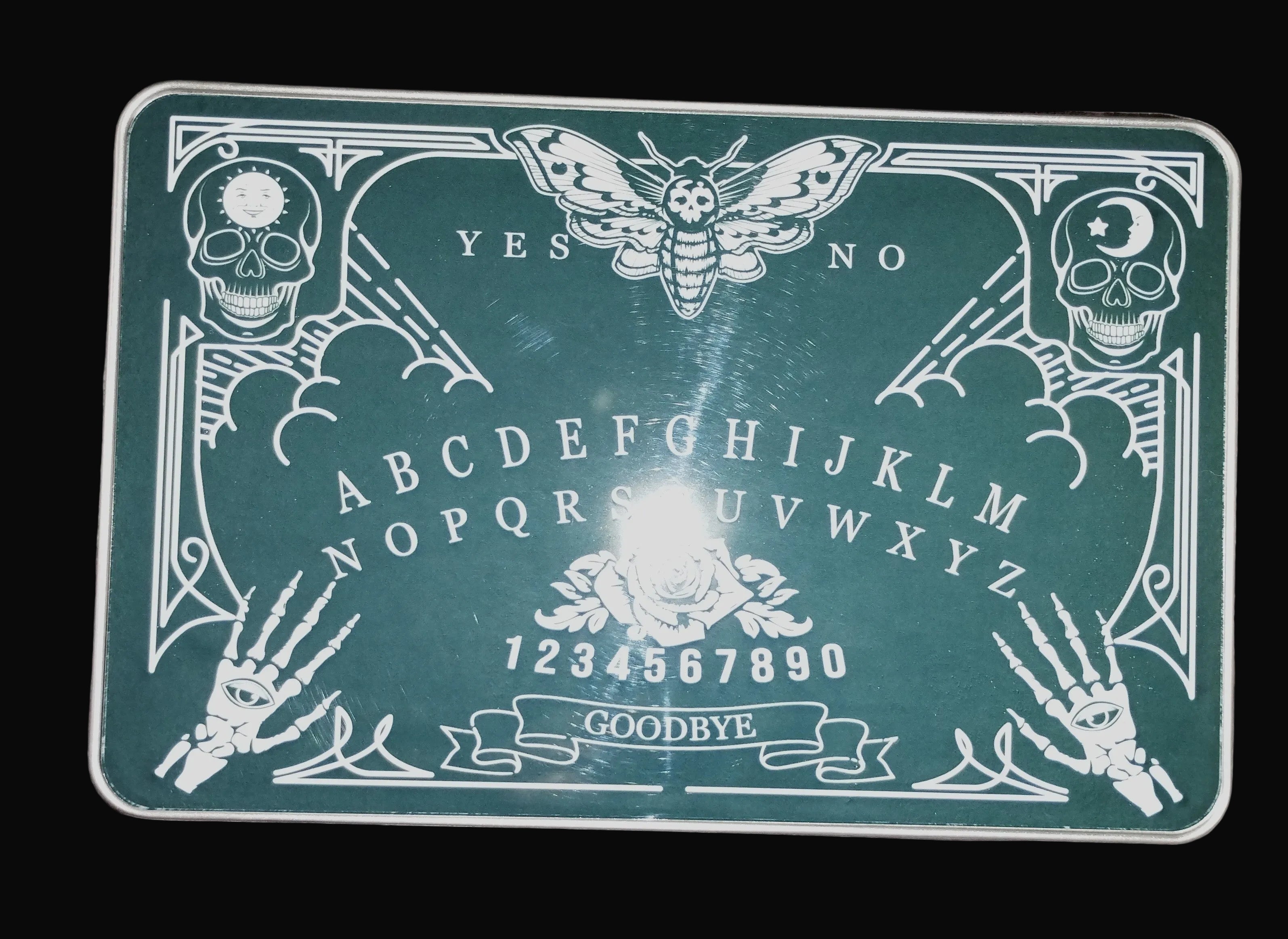 Ouija board with skeleton hands and skulls on a wooden surface