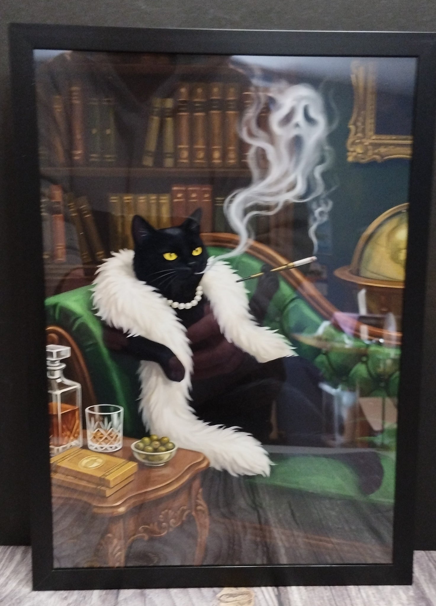 Framed artwork of a black cat in a luxurious setting with books and a smoking cigarette.