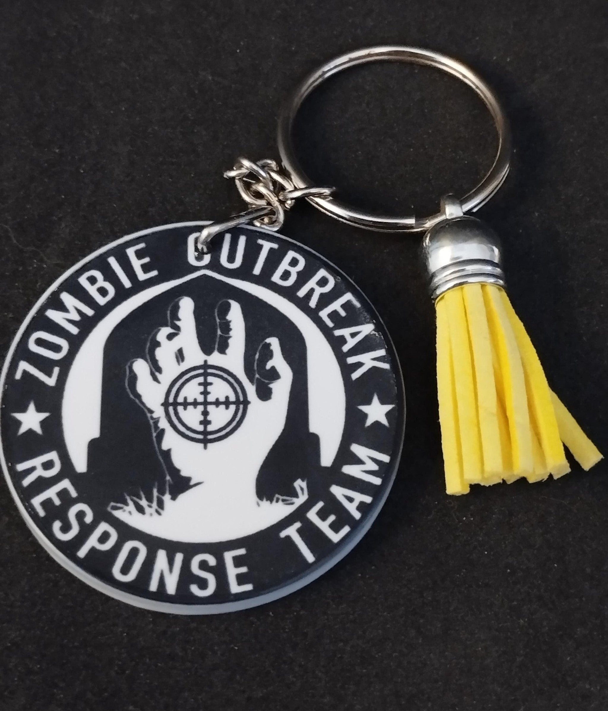 Keychain with 'Zombie Outbreak Response Team' design and yellow tassel on a black background
