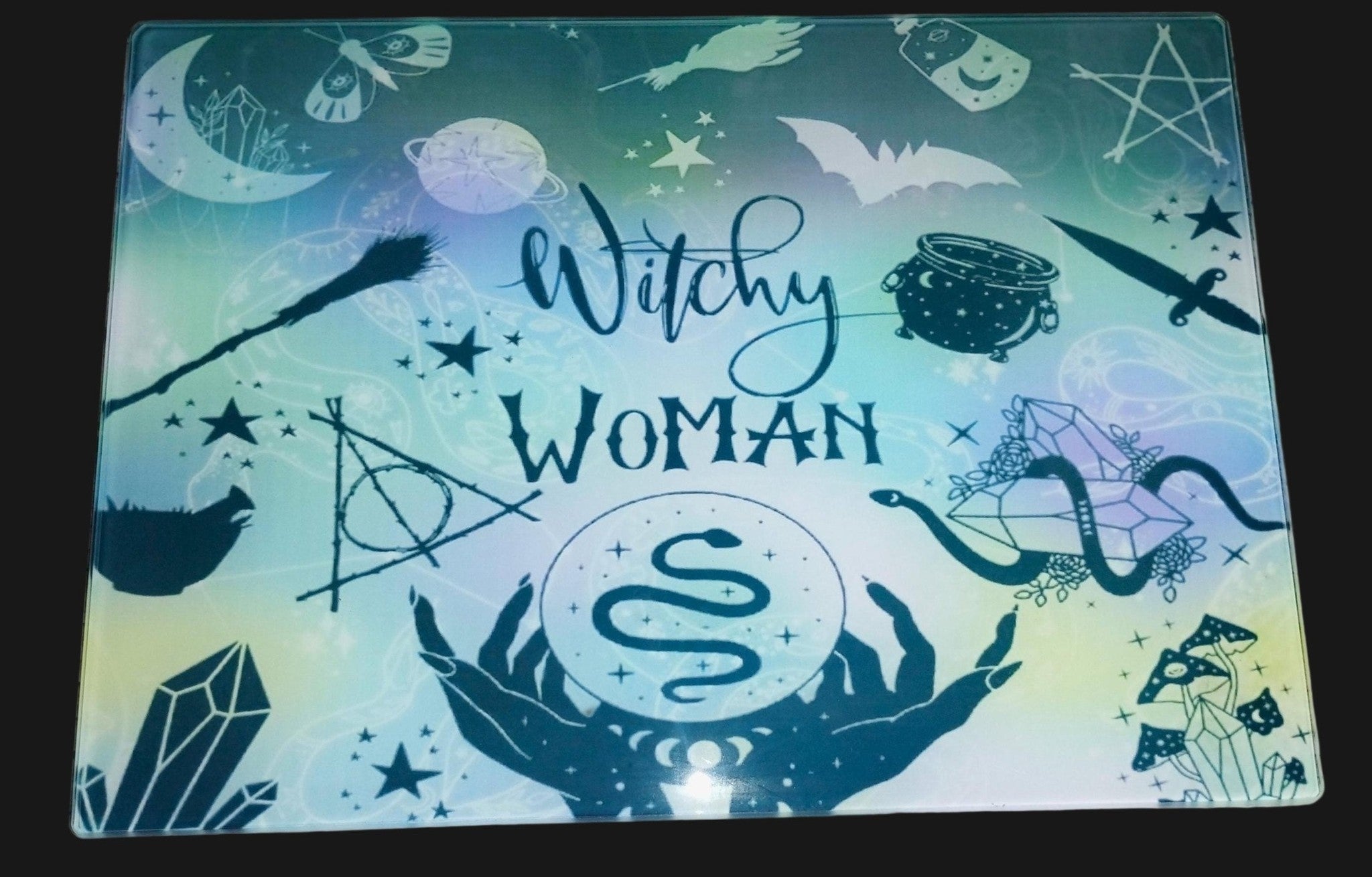 Decorative mat with 'Witchy Woman' text and various symbols on a wooden surface