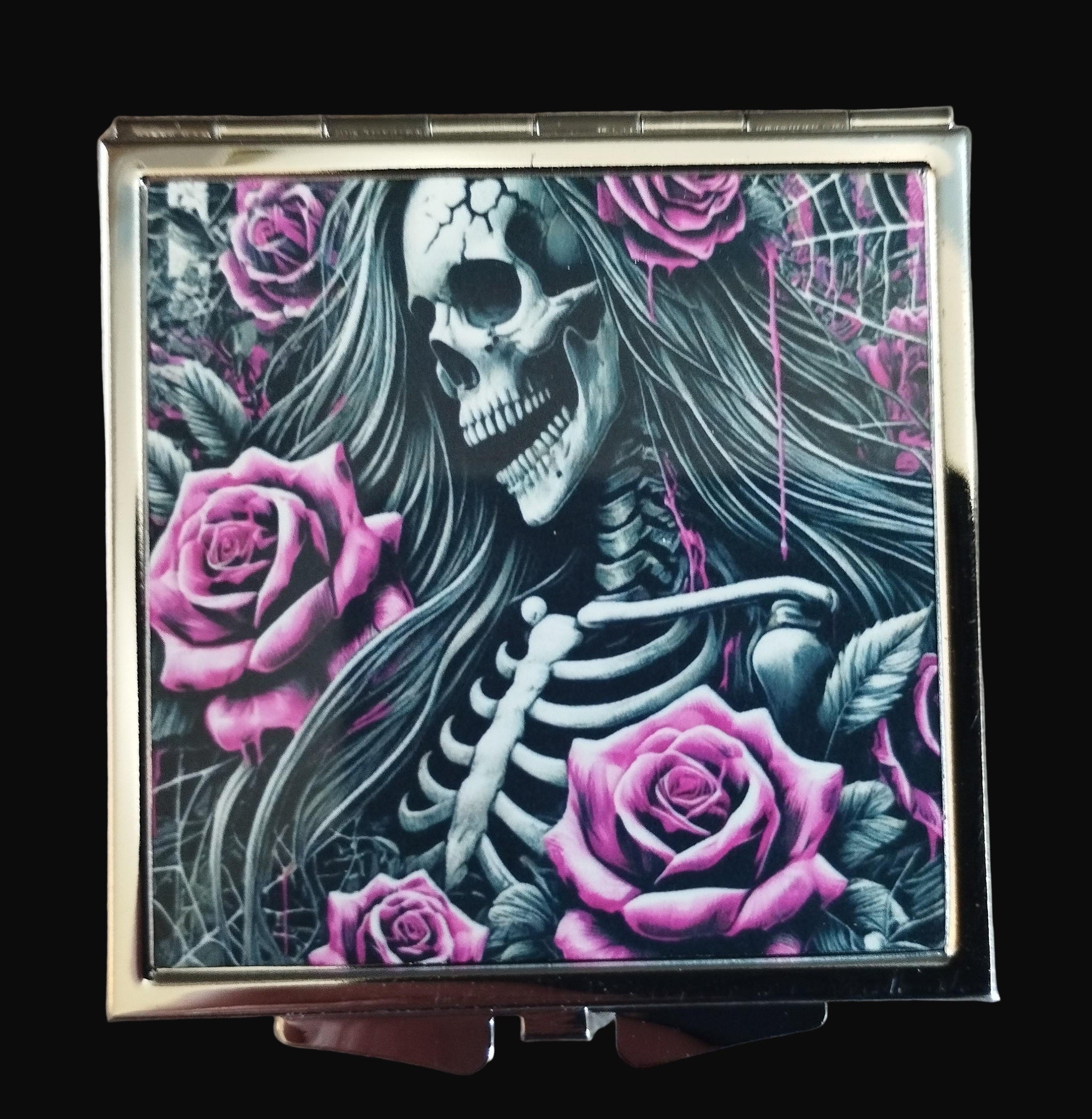 Compact mirror with skeleton and pink roses design on a wooden surface