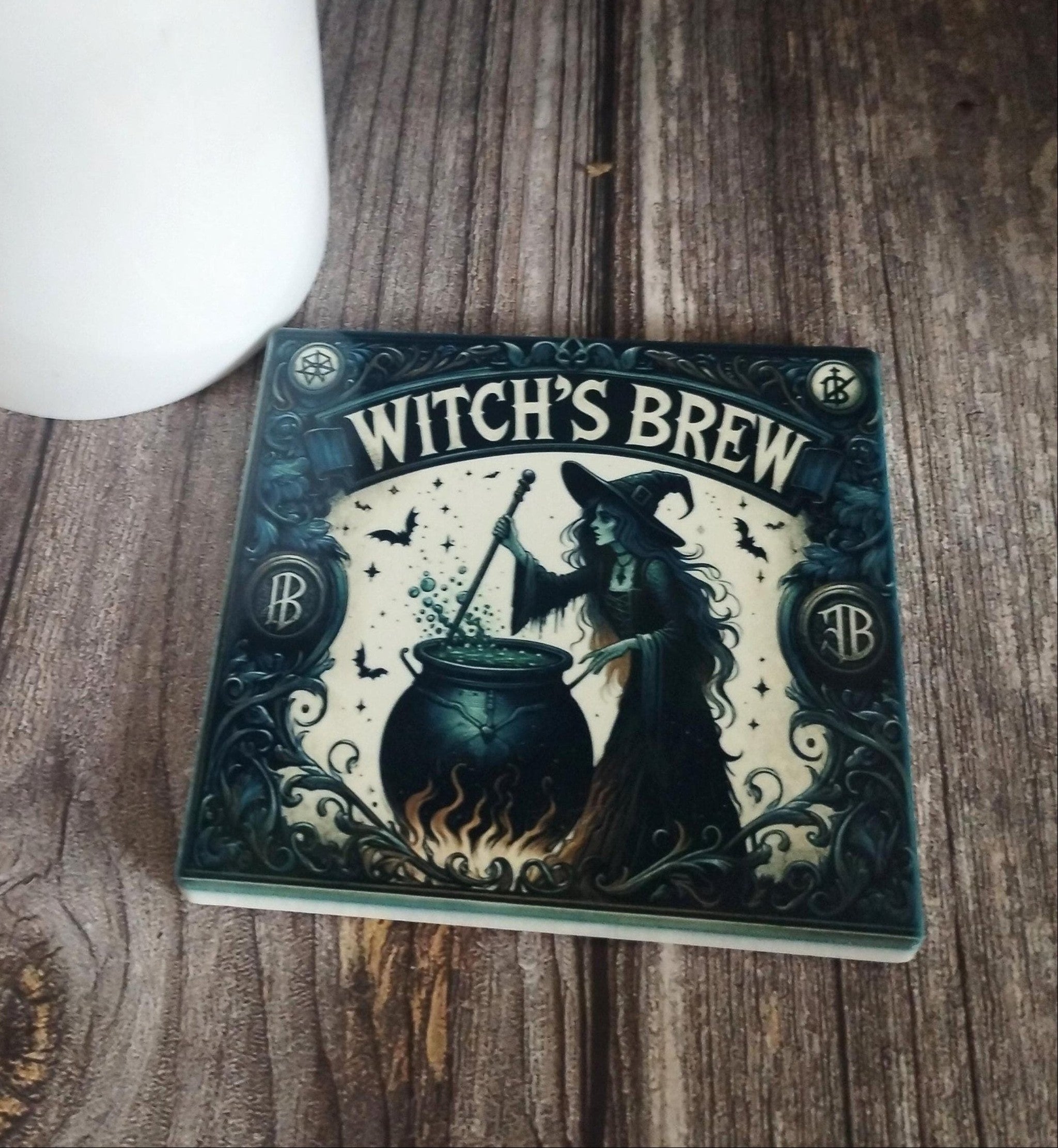 coaster  titled 'Witch's Brew' on a wooden surface with a white vase in the background.