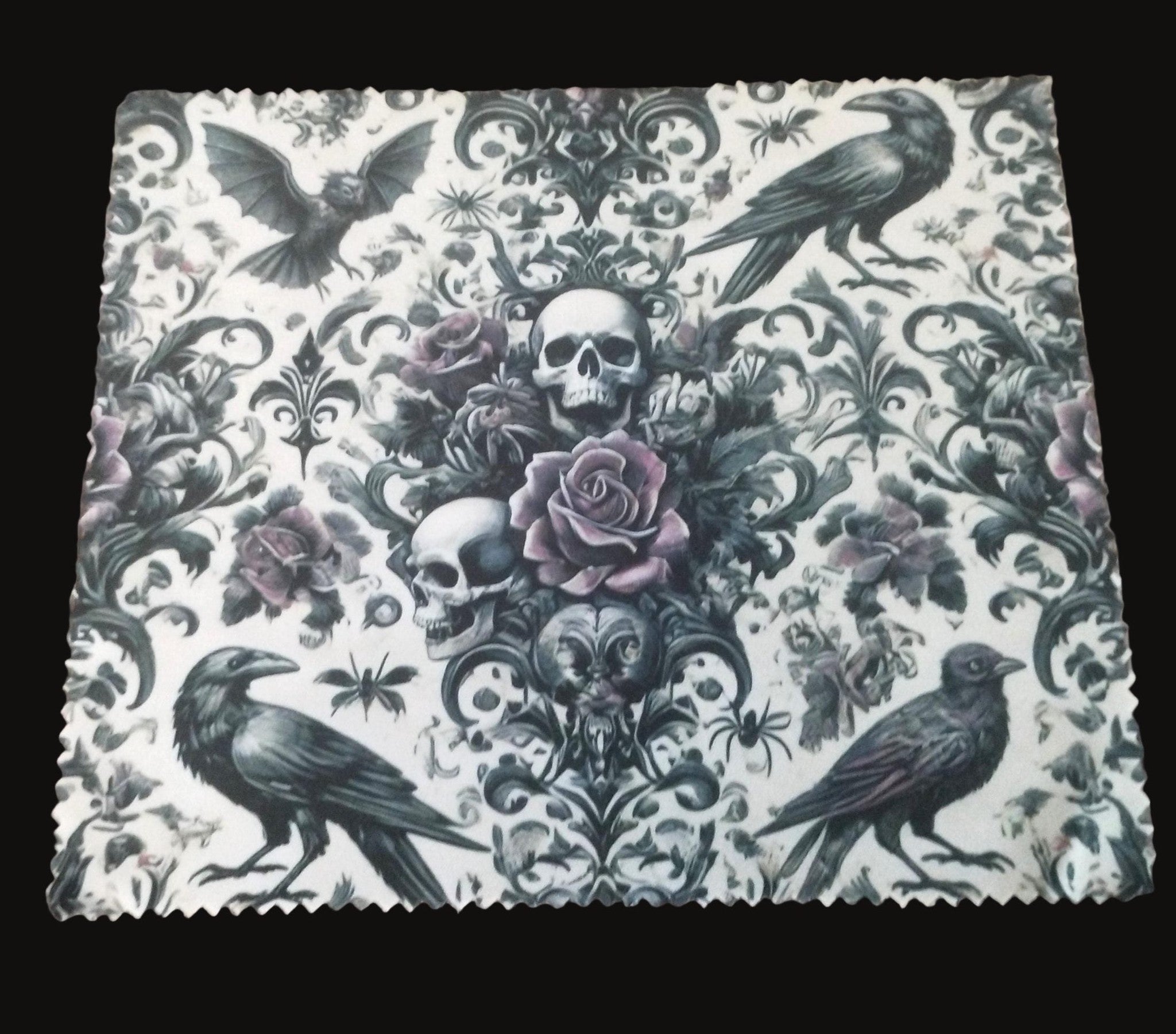Decorative lens cloth with skull, roses, and crows on a wooden surface