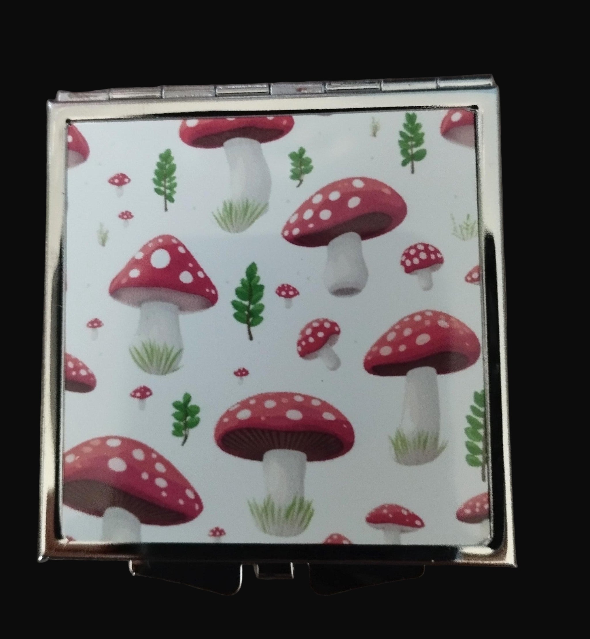 Compact mirror with red mushroom pattern on a wooden surface