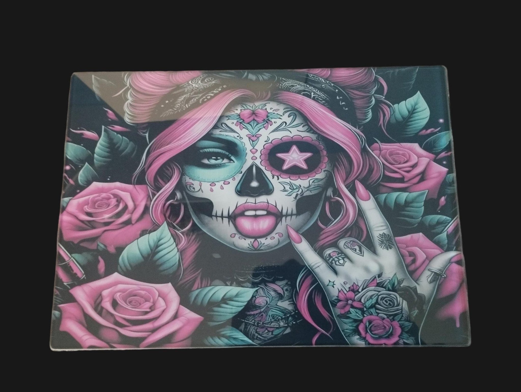 Mouse pad with a colorful skull design and pink roses on a wooden surface