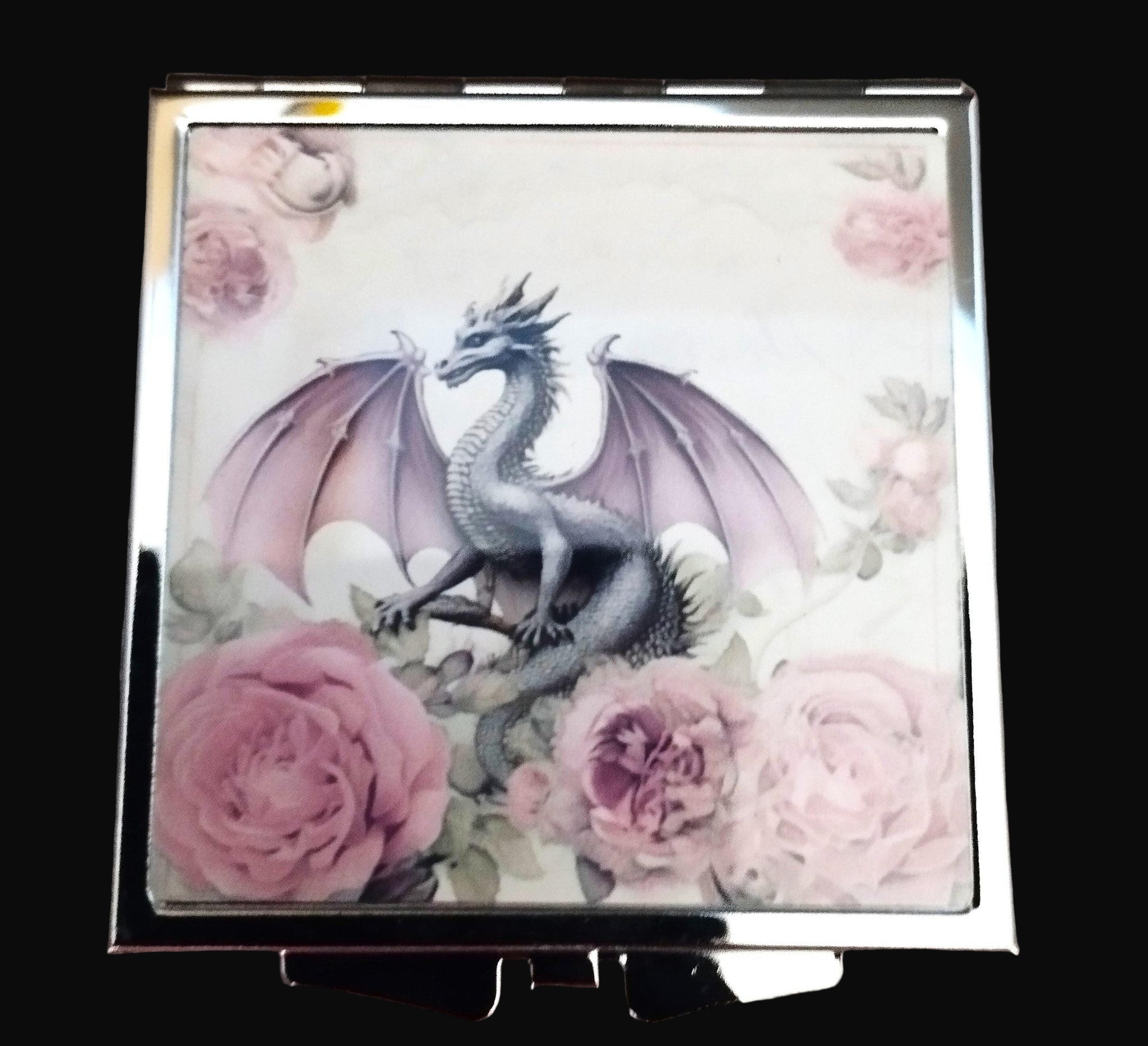Compact mirror with a dragon and floral design on a wooden surface