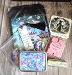 Collection of decorative items including a small bag, tags, and a tin on a wooden surface.