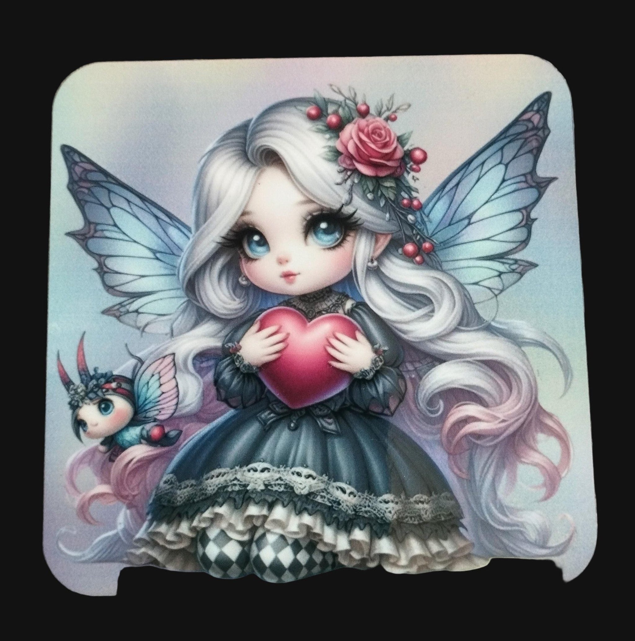 Coaster with a fairy holding a heart with a small creature on a wooden surface