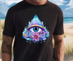 Person wearing a black t-shirt with a colorful eye design on a beach.