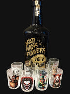 Bottle of Dead Man's Fingers rum with shot glasses featuring various designs on a wooden surface.
