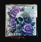 Compact mirror with skull and purple roses design on a wooden surface