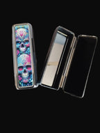 Makeup compact with colorful skull design on a wooden surface