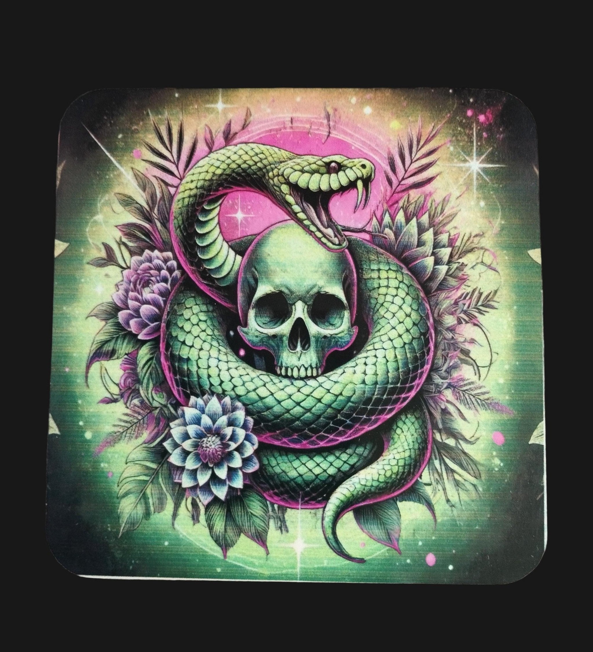 Decorative coaster with a green snake and skull design on a wooden surface