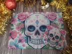Decorative card with colorful skull design and pink flowers on a wooden surface with festive decorations.