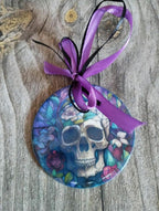 Decorative ornament with skull design and purple ribbon on a wooden surface