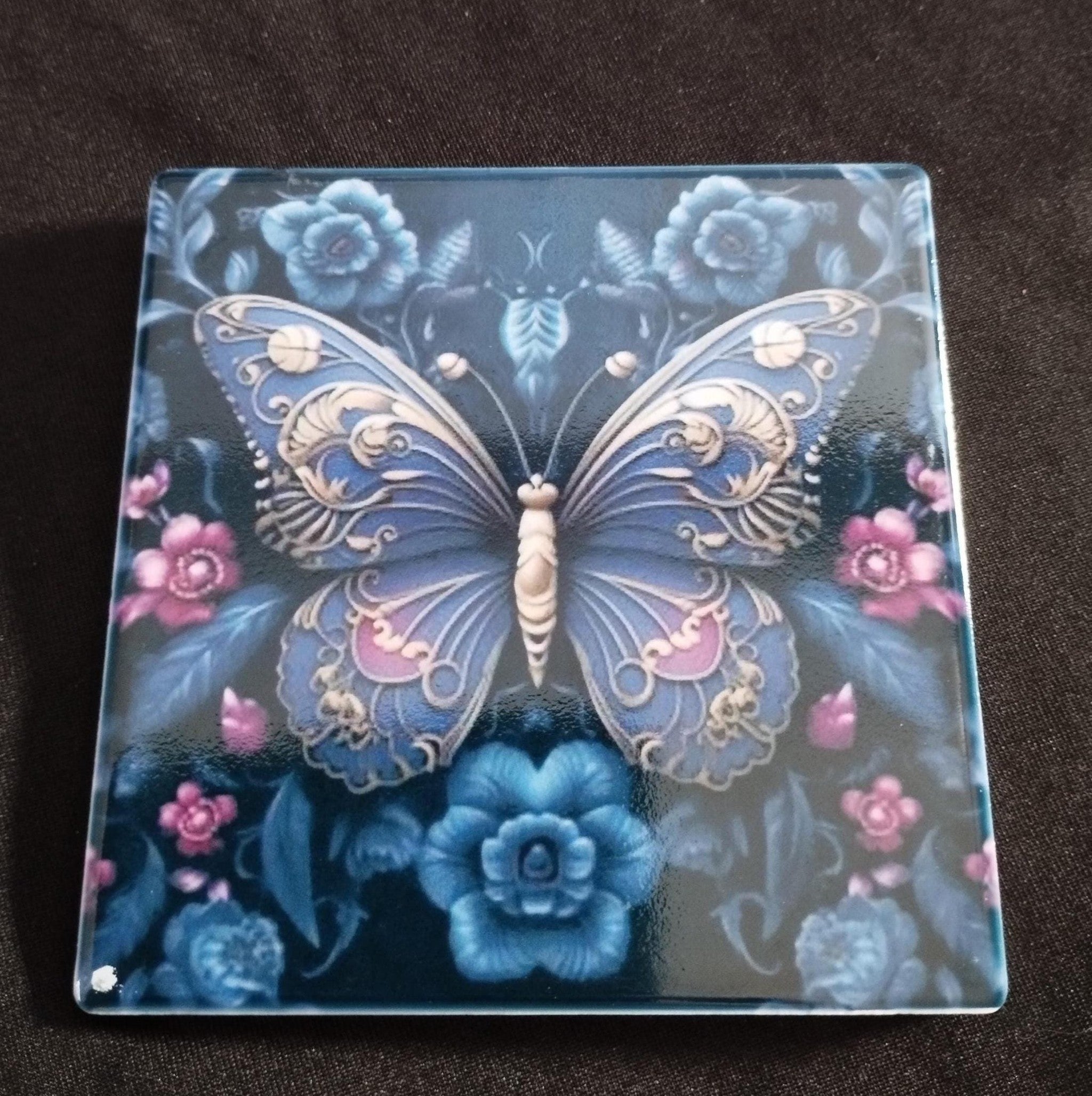 Decorative glass coaster with butterfly and floral design on a dark background