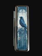 Lipstick case with a crow design on a wooden surface