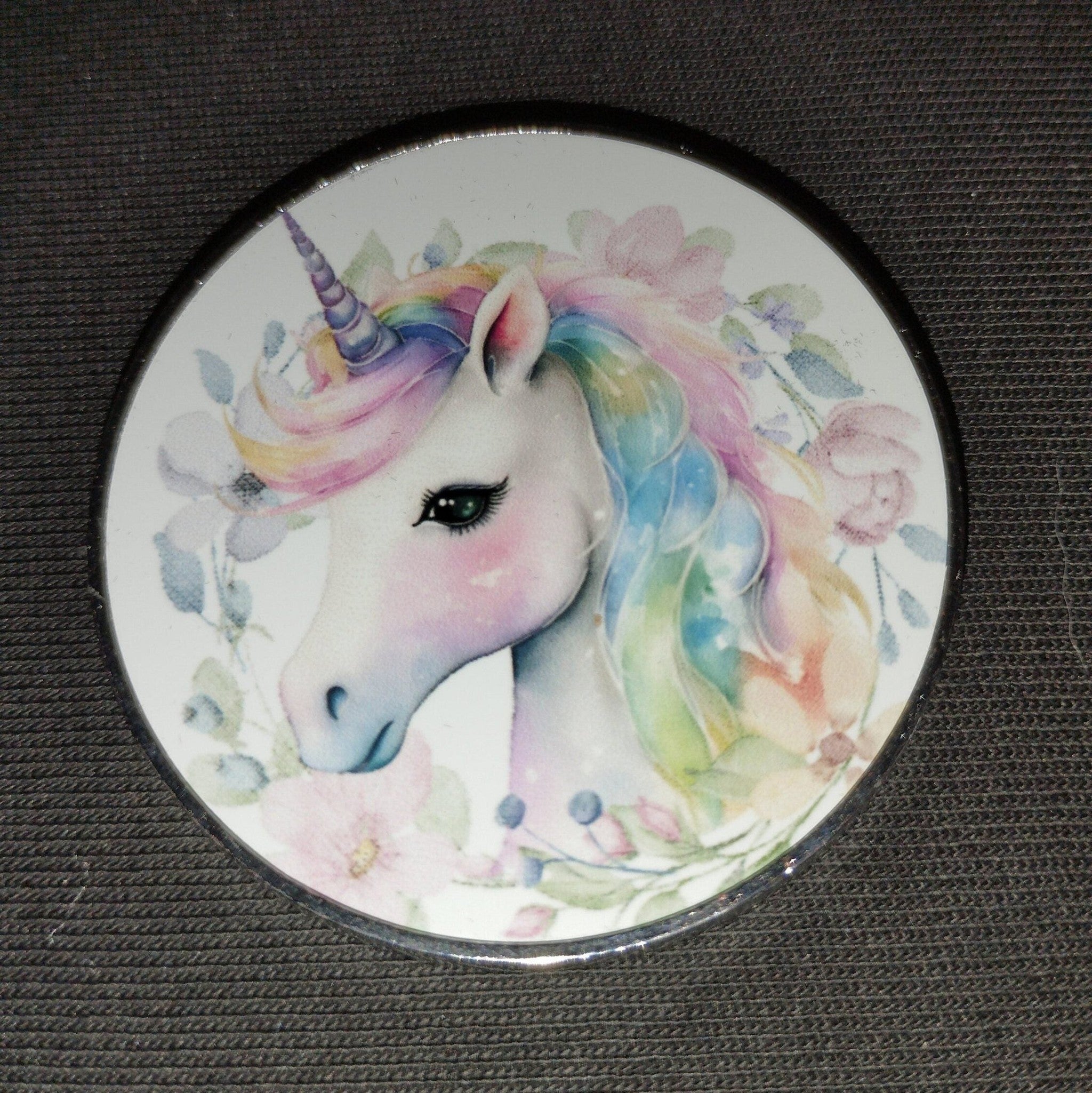 Round magnet with a colorful unicorn design on a dark surface