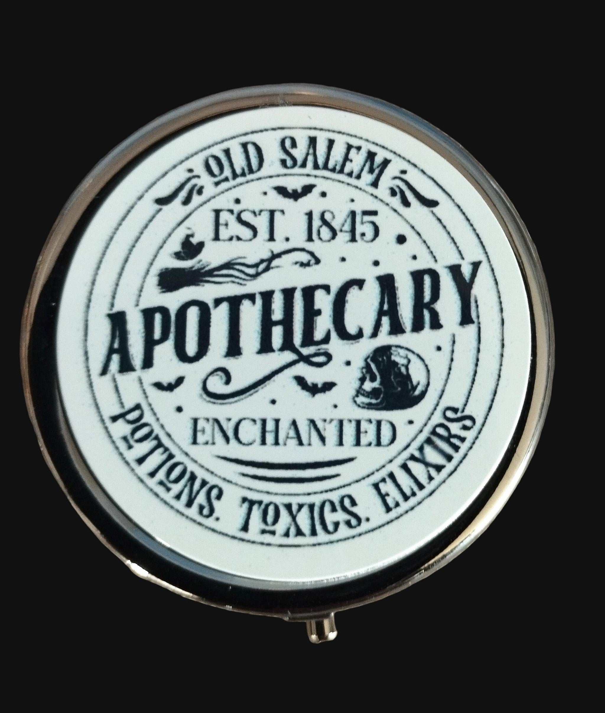 Round pill tin with 'Old Salem Apothecary' text on a wooden background