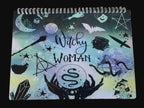 Notebook with 'Witchy Woman' design on a wooden surface
