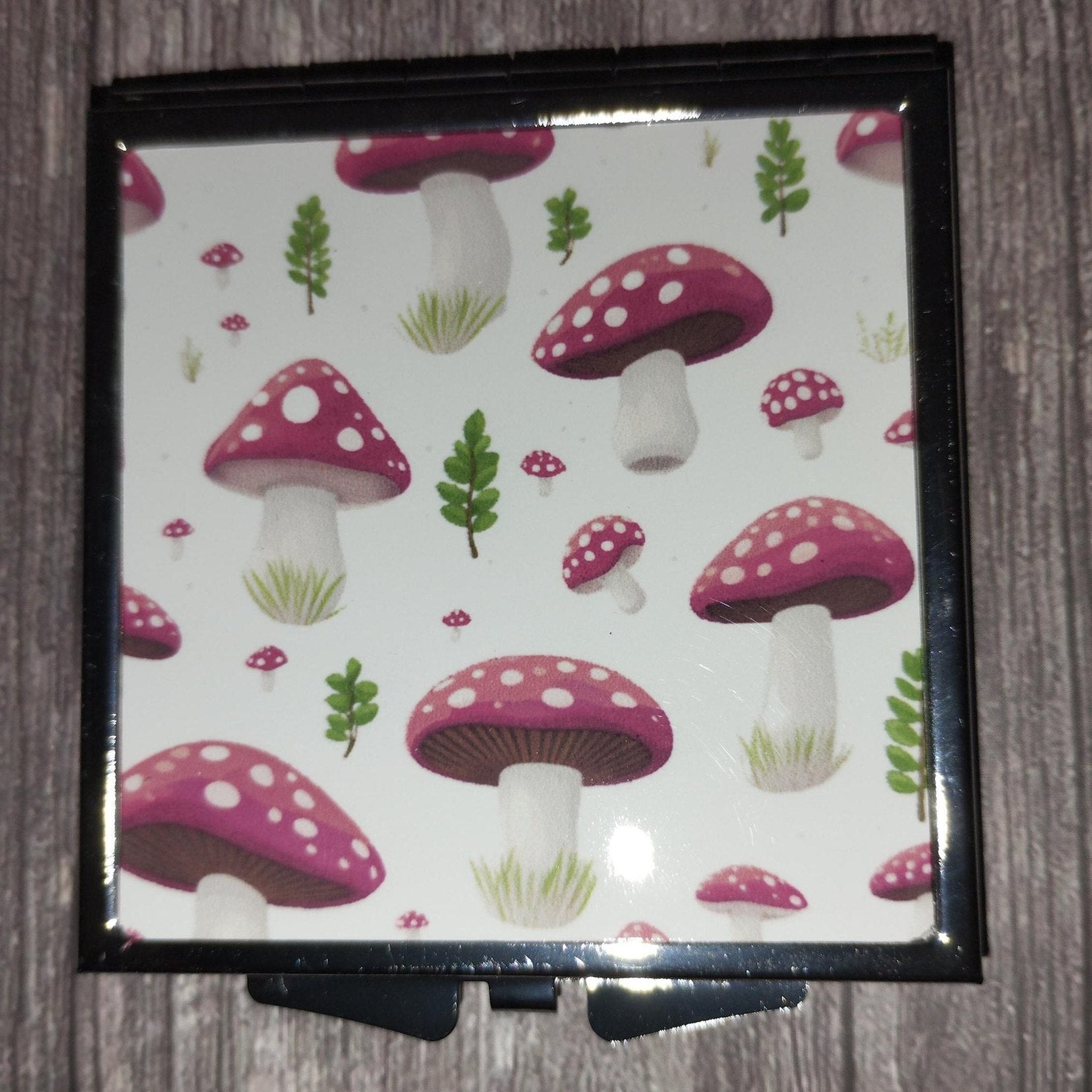 Compact mirror with mushroom pattern on a wooden surface