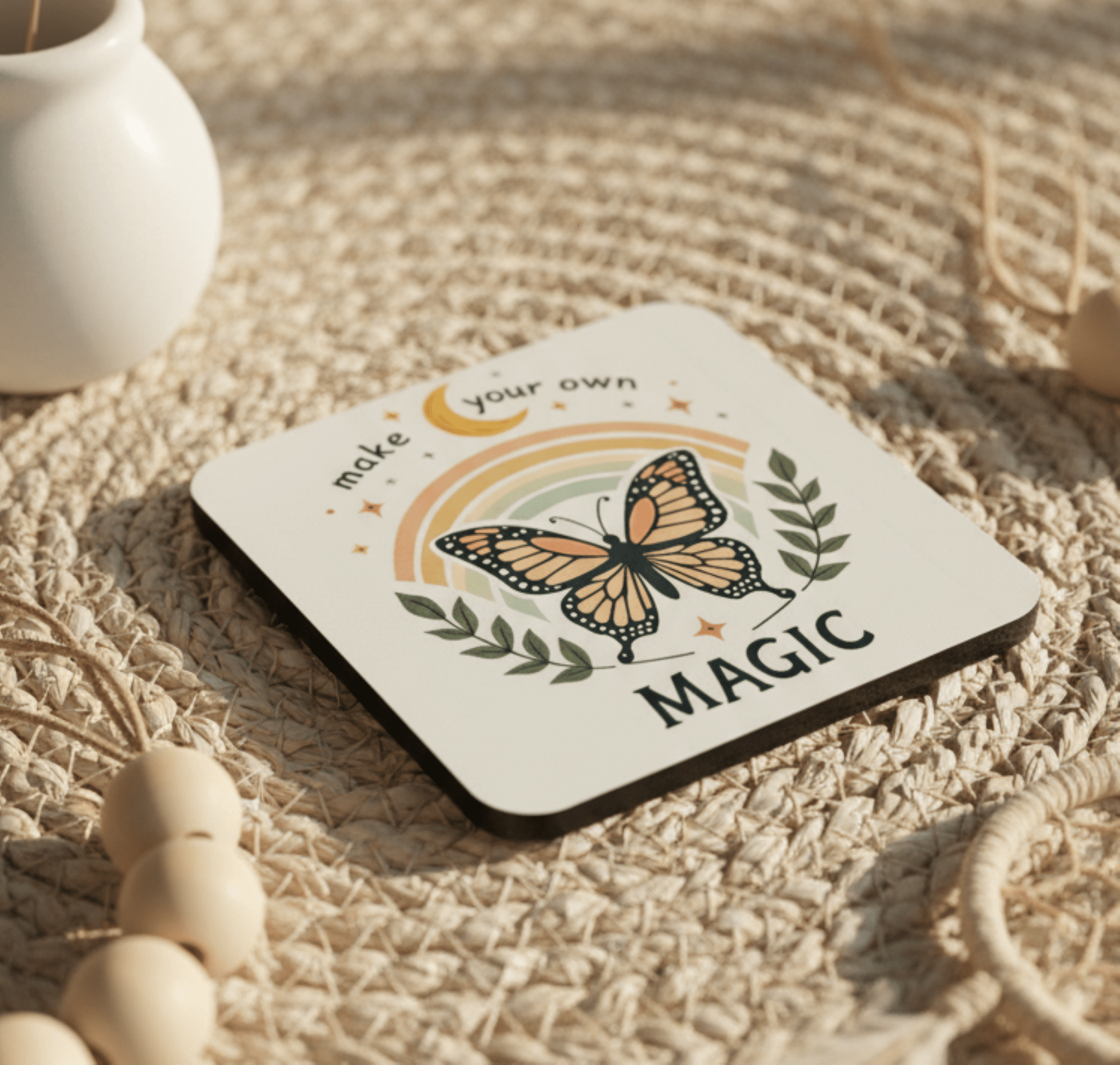 Coaster with butterfly design and text 'make your own magic' on a woven surface