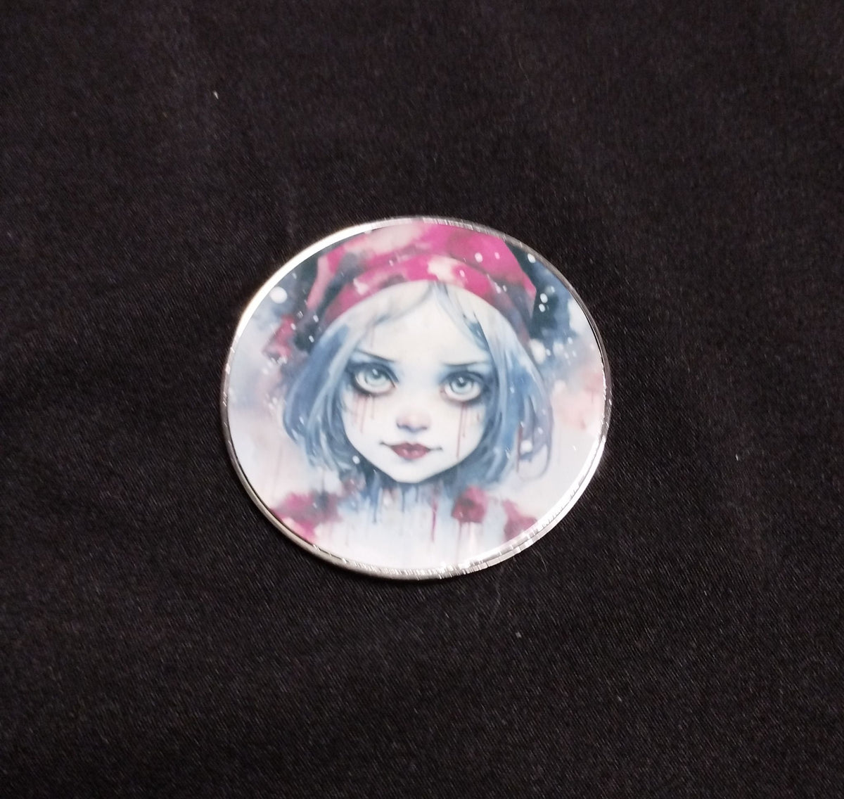 Round fridge magnet showing a pale blue-haired girl in a red winter hat against a snowy pink background
