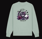 Light green long-sleeve shirt with a graphic design of a cat, moon, roses, and skull on a white background.