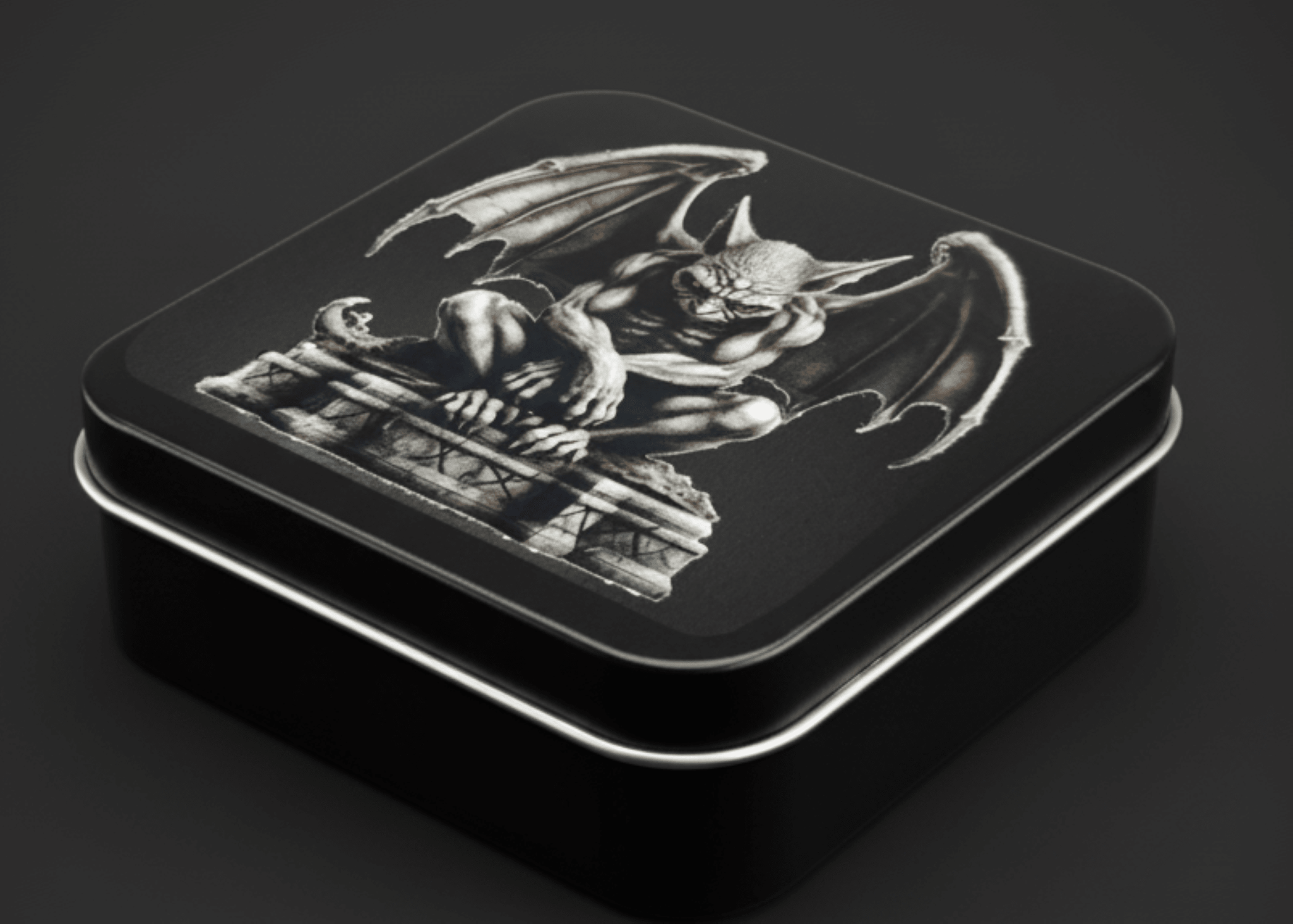 Decorative tin box with a gargoyle design on a dark background