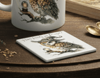 Mug and coaster with owl design on a wooden surface