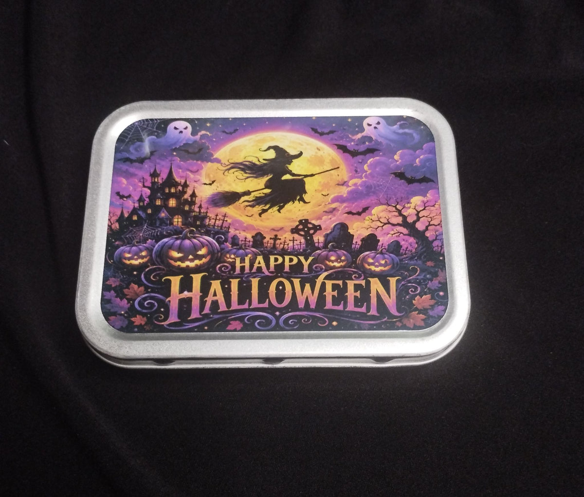Happy Halloween metal trinket tin featuring a witch flying across the moon, pumpkins and a haunted house