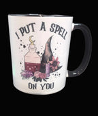 Mug with witch hat, potion, and flowers design with text 'I put a spell on you' on a dark background