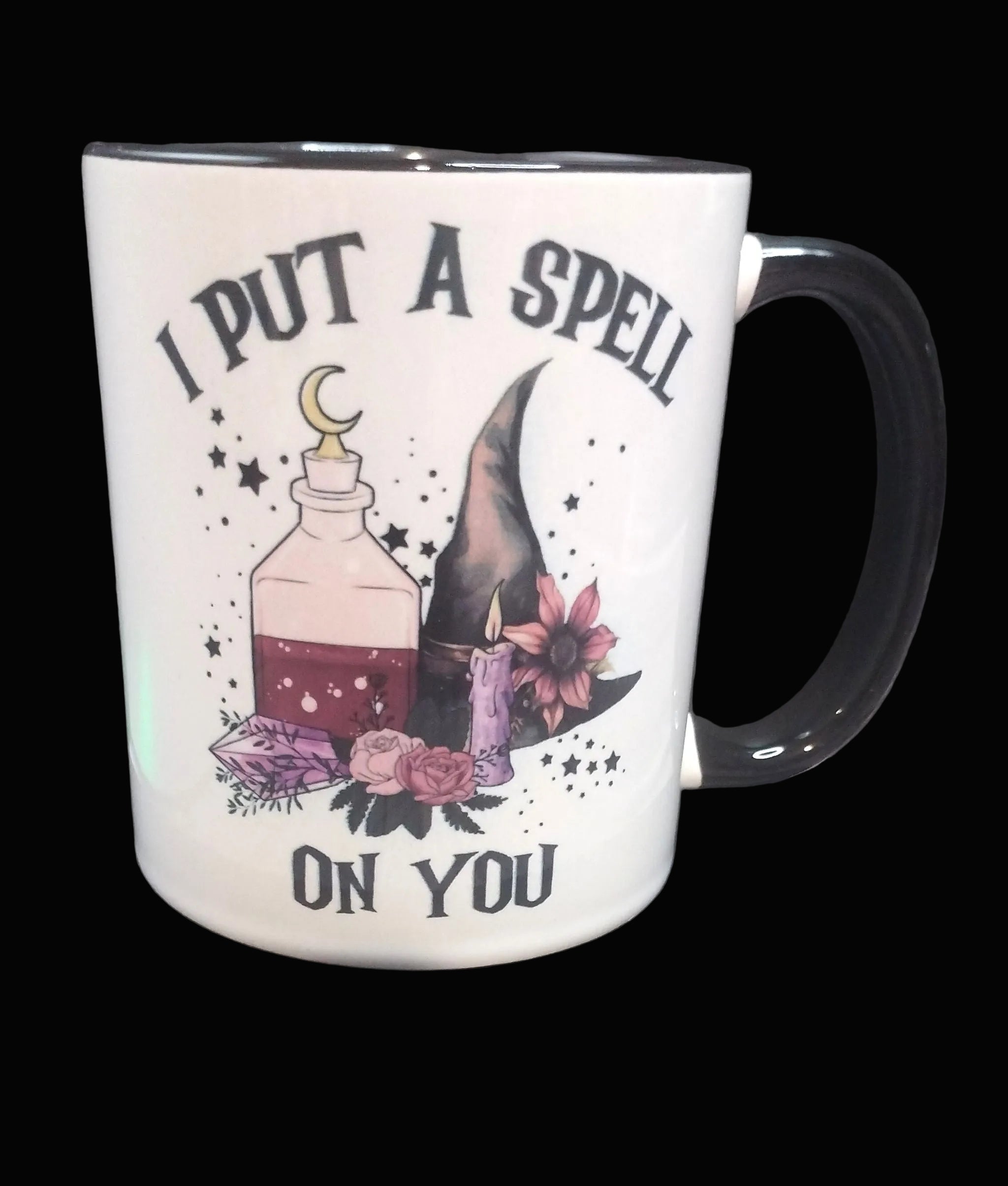 Mug with witch hat, potion, and flowers design with text 'I put a spell on you' on a dark background