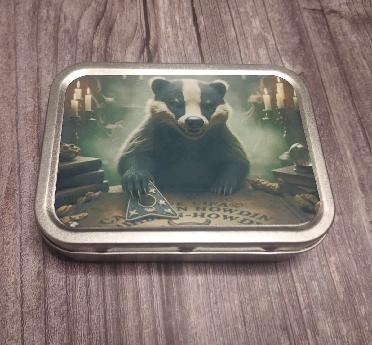 Small metal trinket tin featuring a badger seated at a Ouija board by candlelight