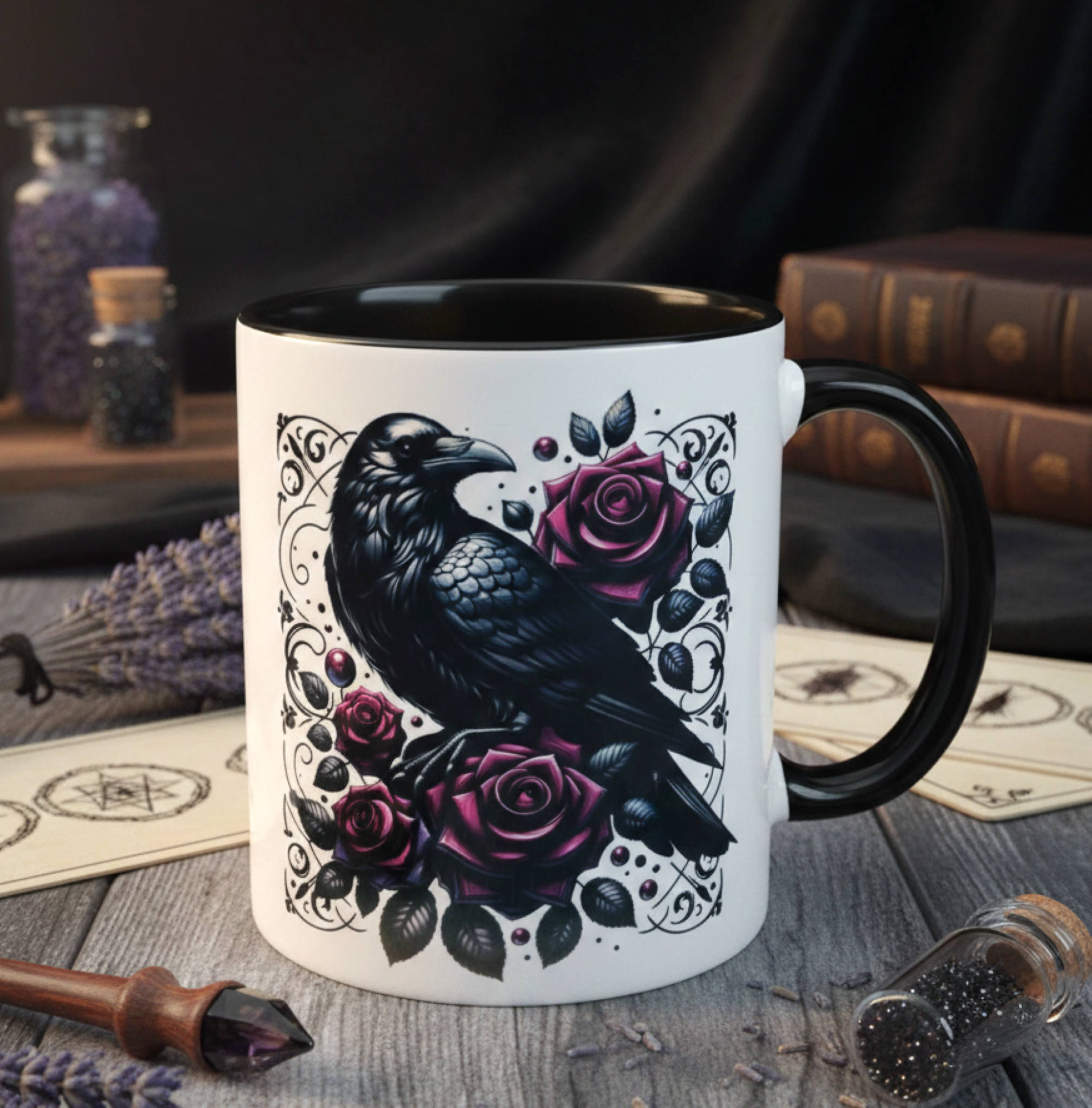 Mug with a black crow and pink roses design on a wooden surface with books and lavender.