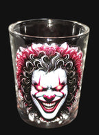 Glass shot glass with a clown design on a dark background