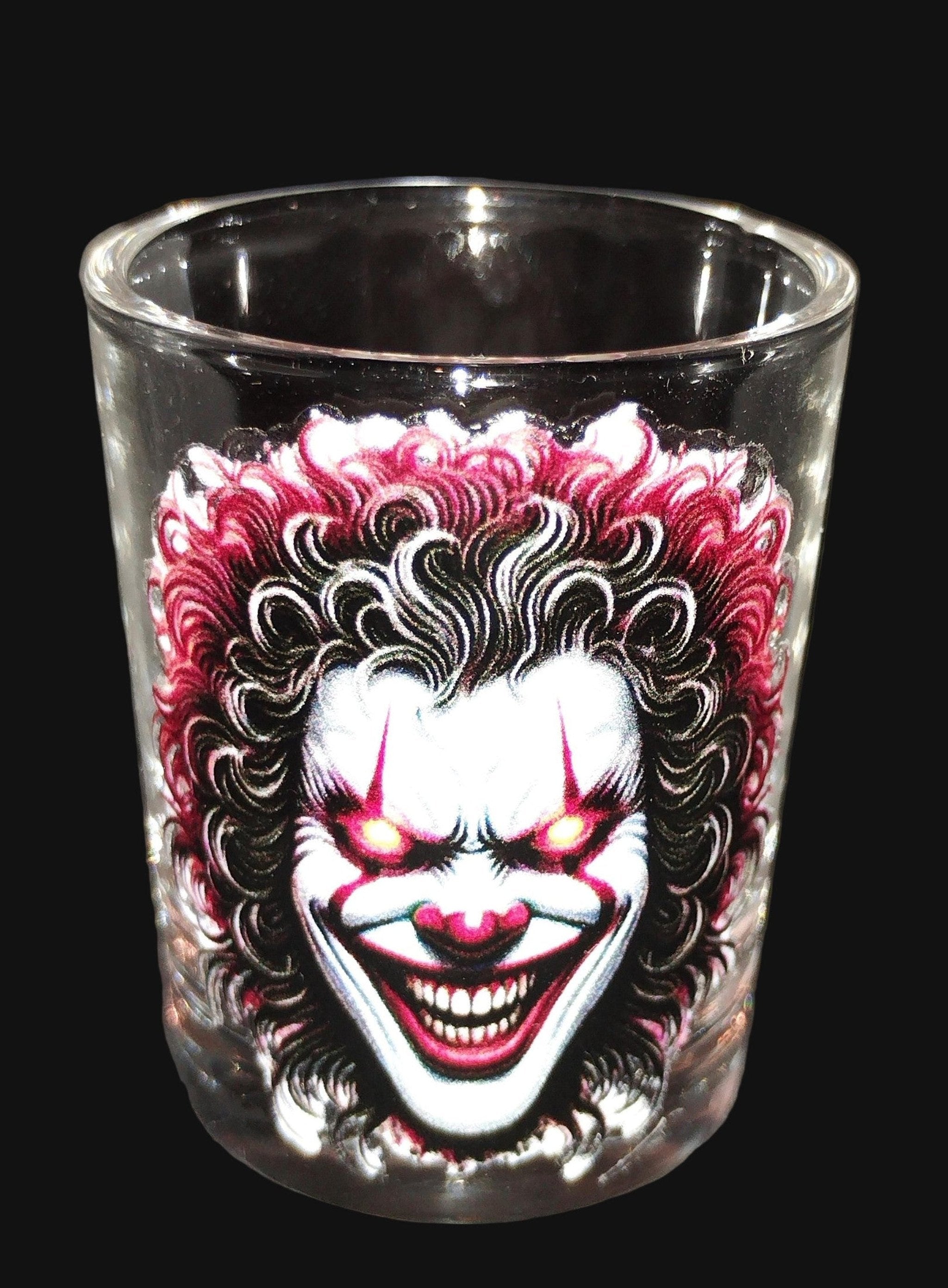 Glass shot glass with a clown design on a dark background