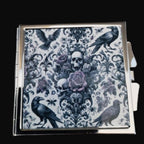 Decorative box with skull and crow design on a wooden surface