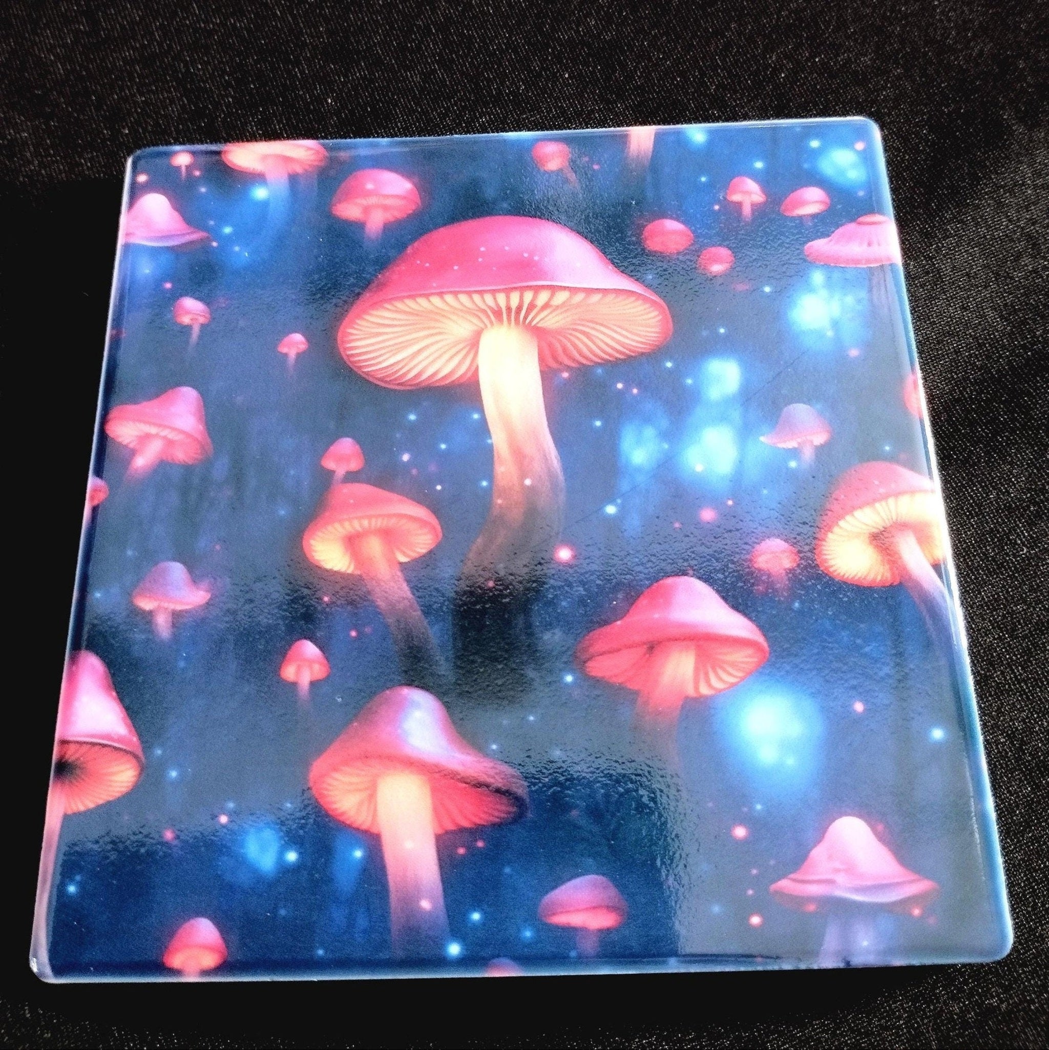 Glass coaster with pink mushrooms design on a dark background