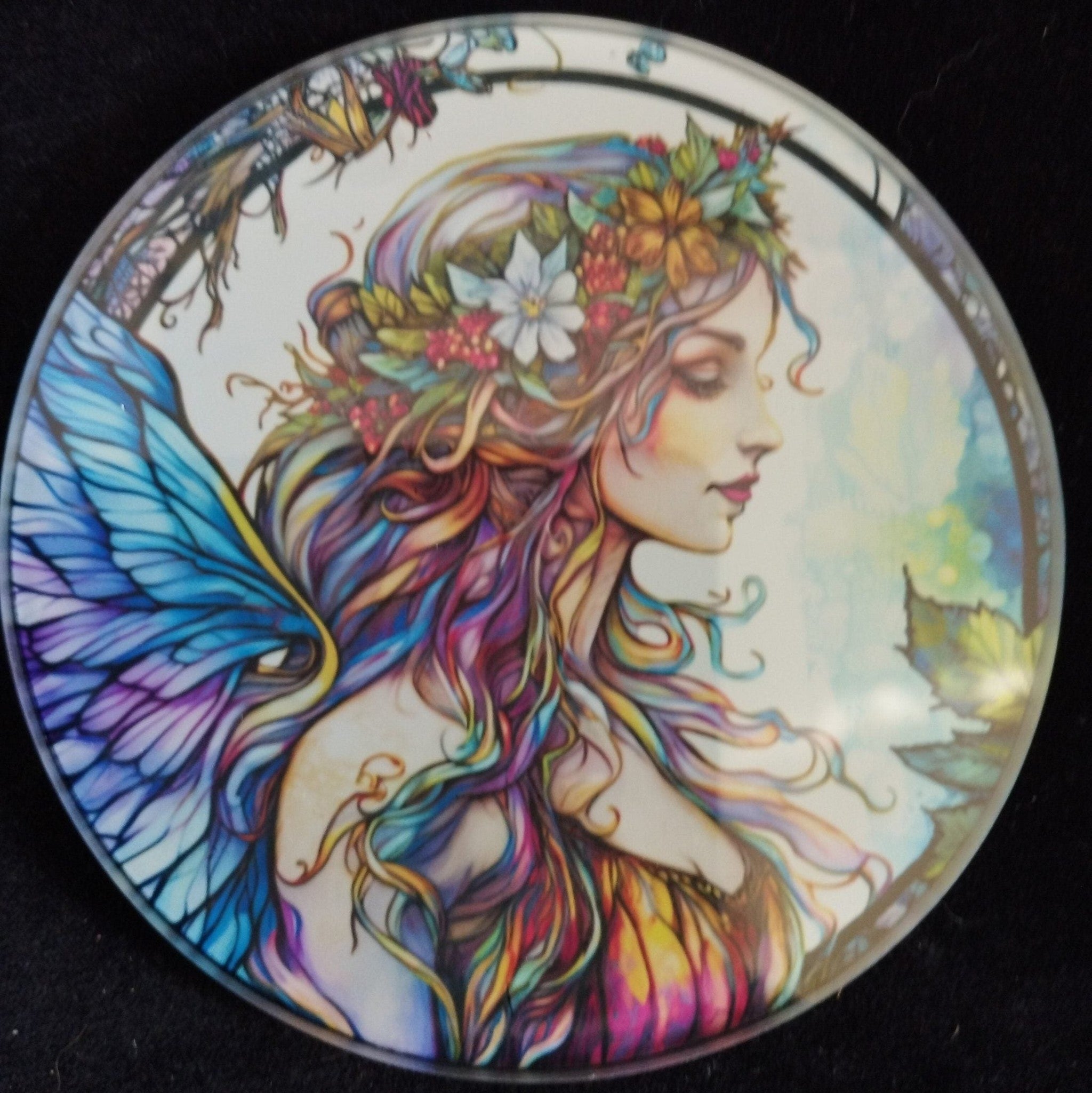 Round decorative item with a colorful fairy design on a black background